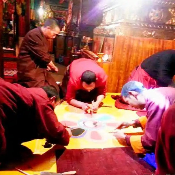 Monks painting Thangka on silk, showing traditional hand-painted craftsmanship and religious art